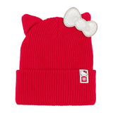 A bright red ribbed knit beanie hat with cat ears on top and a large white bow on the side, featuring a small Hello Kitty patch on the cuff. 