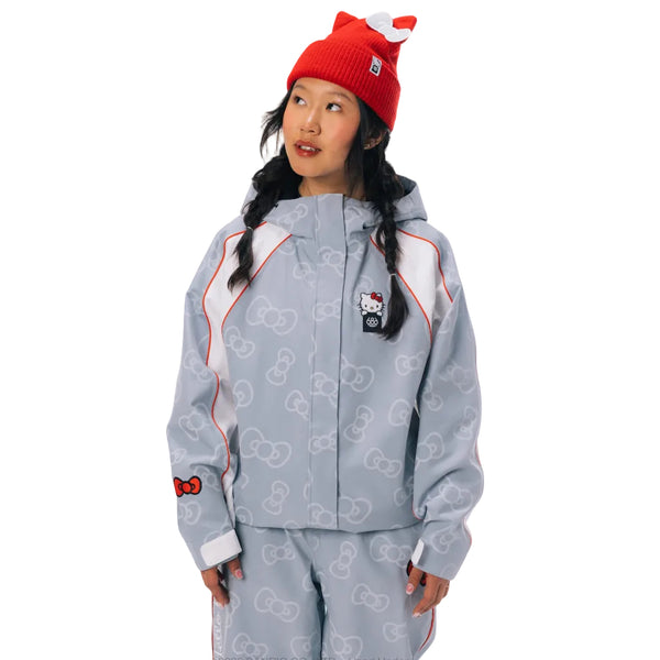 A model wearing a light blue Hello Kitty zip-up jacket and matching pants, styled with a red cat-ear beanie