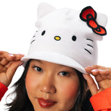A white knit Hello Kitty beanie hat with a red bow