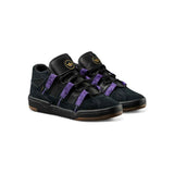 A pair of Adidas  sneakers in black suede and leather with prominent purple elastic straps and a gold logo on the tongue, set against a plain white background.