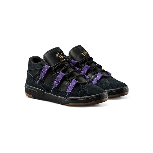 A pair of Adidas  sneakers in black suede and leather with prominent purple elastic straps and a gold logo on the tongue, set against a plain white background.